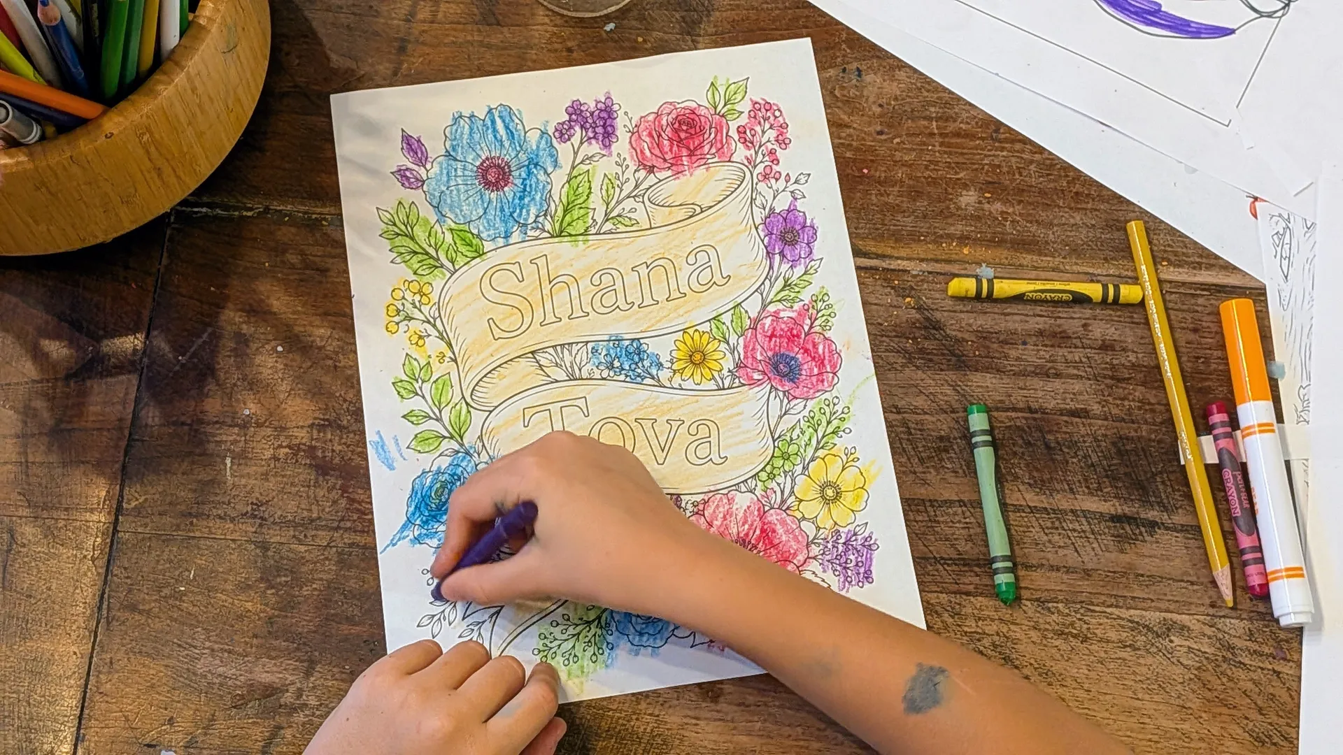 Child coloring a Rosh Hashanah coloring page from the activity bundle