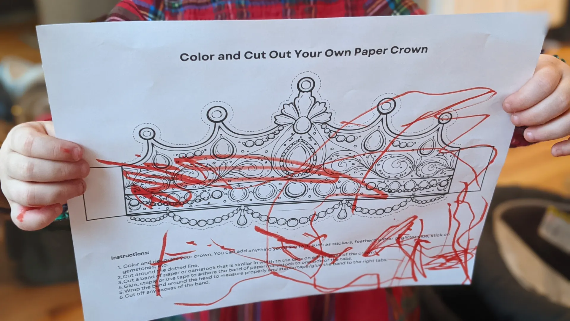 Child holding up a completed paper crown coloring page
